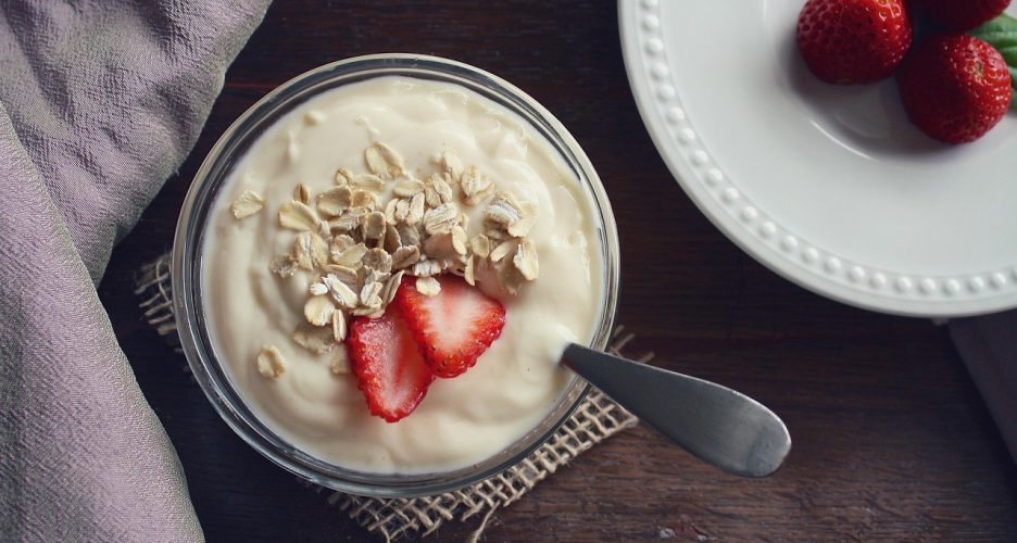 Domowy jogurt naturalny w szklanym słoiku z płatkami owsianymi i truskawkami